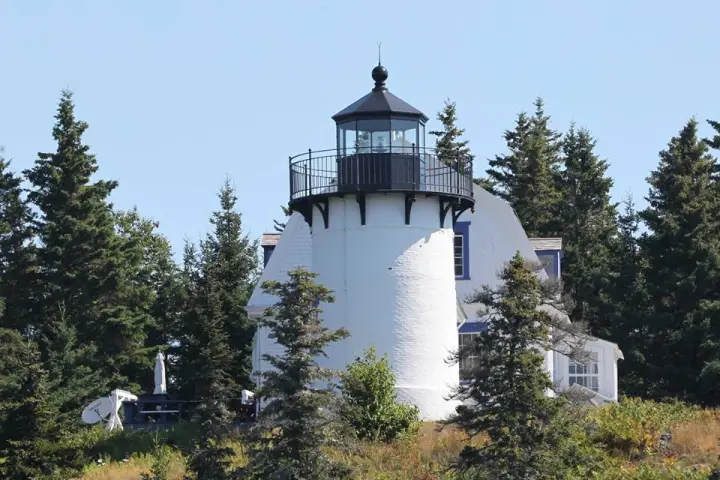 small tower near a forest with Old Presque Isle Light in the background