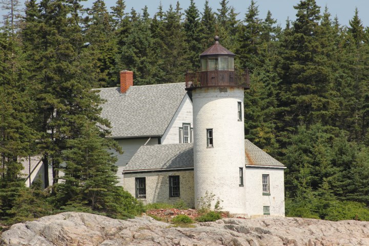 an old stone building with Mission Point Light in the background